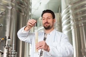 Brewer standing in his brewery and is examining the beer for its